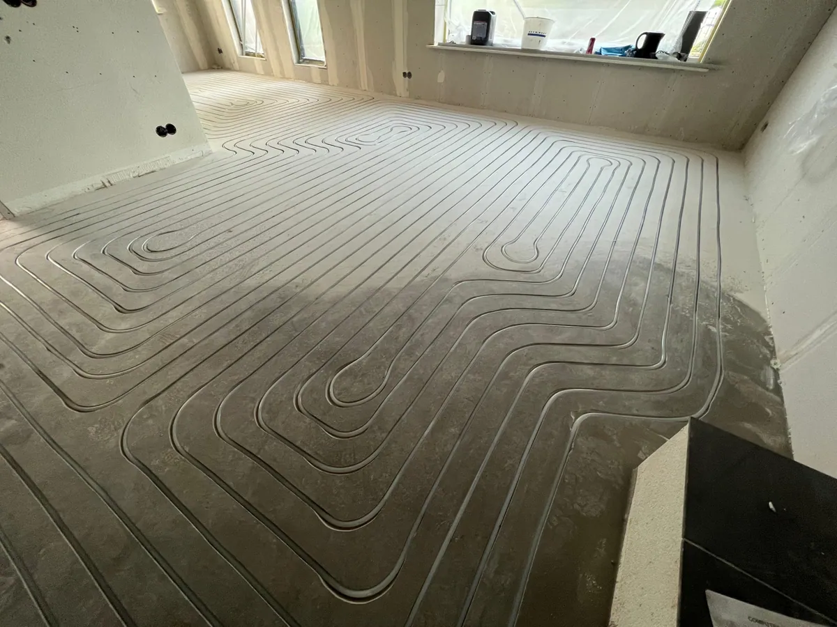 Detail van gefreesde sleuven in dekvloer met vloerverwarmingsleidingen